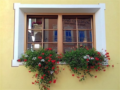 Kleurrijk bloemenraam in een Italiaanse stijl gevel, Val Gardena.